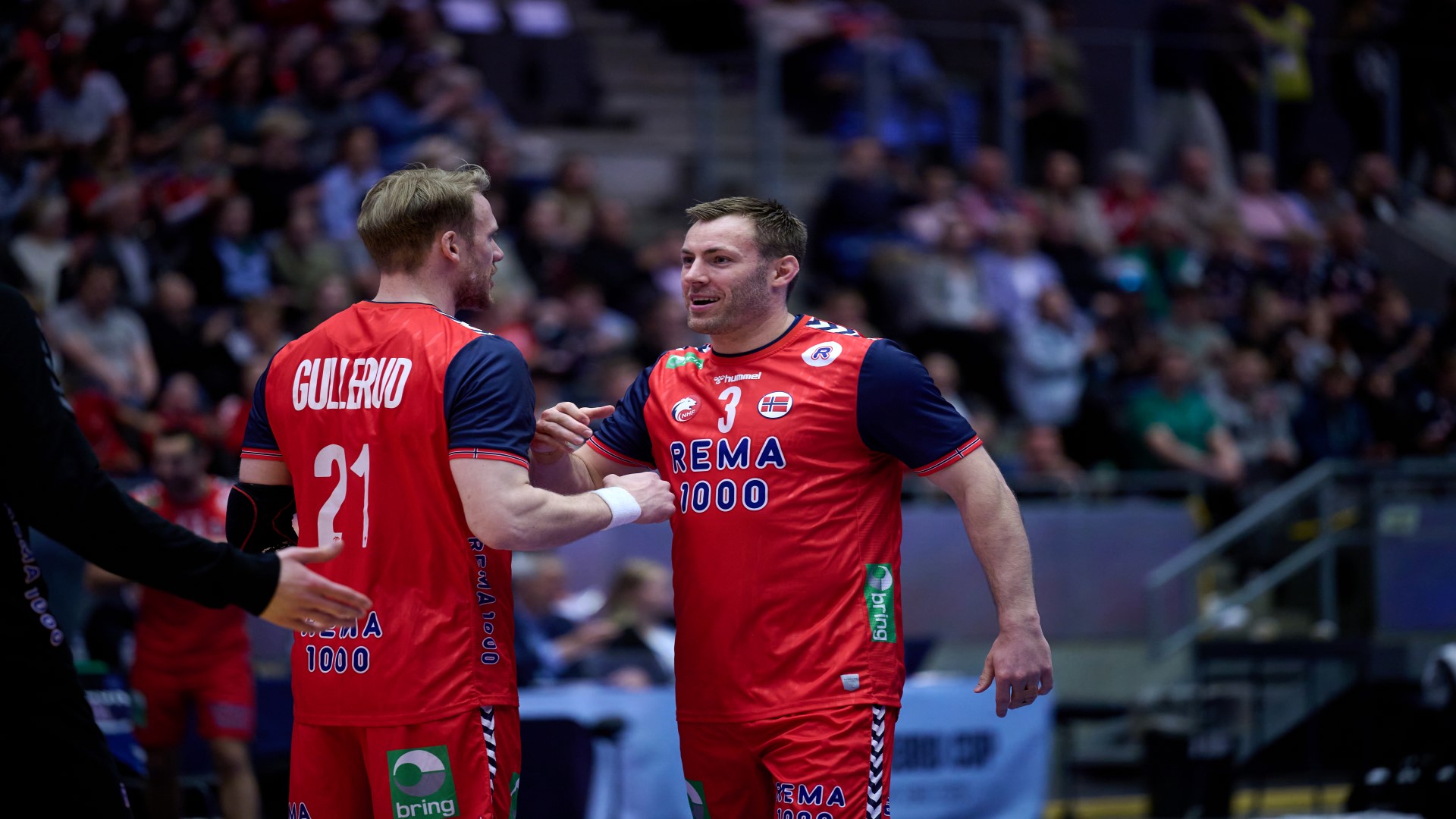 To håndballspillere for Norge i landskamp på banen som står mot hverandre og prater.