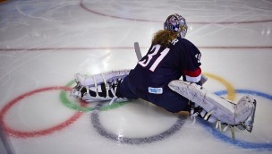 Ishockeymålvak som tar en spagar på isen i ishockeyutstyr.