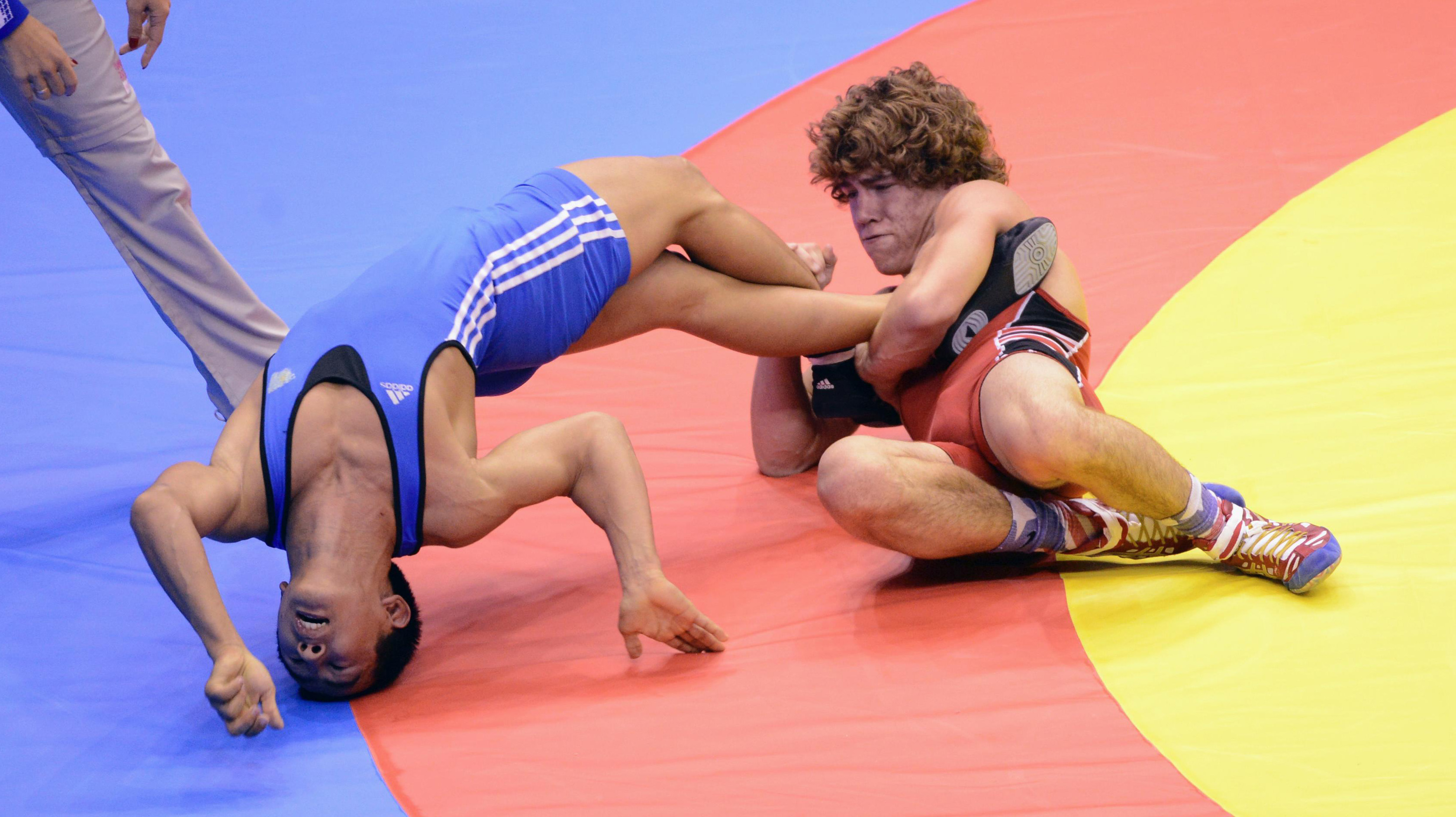 To brytere i kamp på matten, der en har hodet i bakover i bakken mens den andre holder igjen foten hans